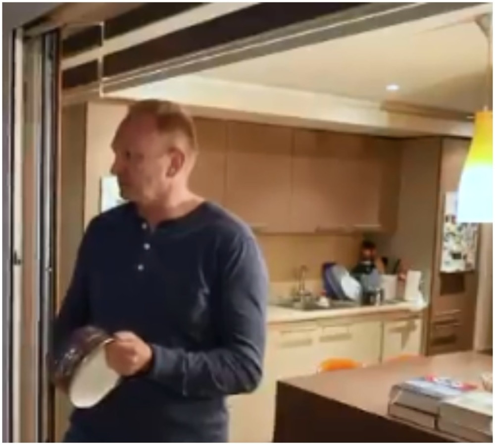 Đilas daje intervju, lupa u šerpu, a u pozadini stoji knjiga sa kukastim krstom